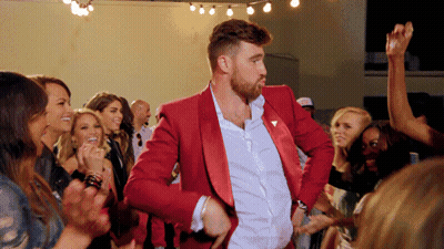 A Man In A Red Suit Is Dancing With A Crowd Of People GIF