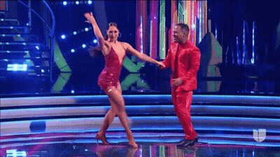 A Man In A Red Suit Is Dancing With A Woman In A Red Dress . GIF