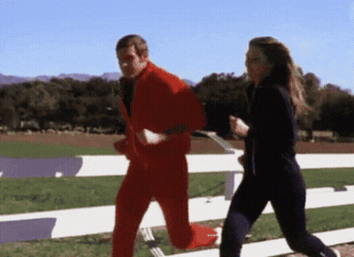 A Man In A Red Suit Is Running With A Woman In Black Pants GIF