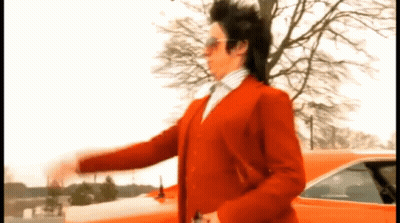 A Man In A Red Suit Is Standing In Front Of A Red Car GIF
