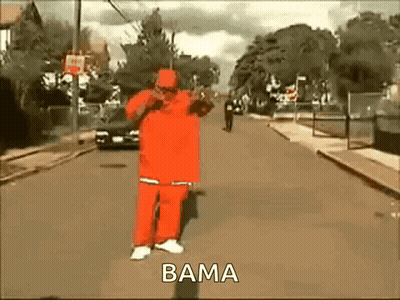 A Man In A Red Suit Is Walking Down A Street With The Word Bama On The Bottom . GIF