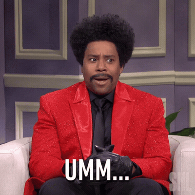 A Man In A Red Suit Says Umm While Sitting On A Chair GIF