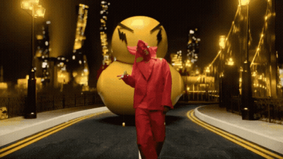 A Man In A Red Suit Stands In Front Of A Large Yellow Ball GIF