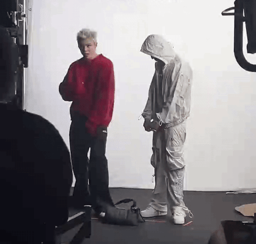 A Man In A Red Sweater And A Man In A White Suit Are Standing Next To Each Other In A Room . GIF