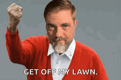 A Man In A Red Sweater Holds His Fist Up And Says " Get Off My Lawn " GIF