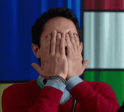A Man In A Red Sweater Is Covering His Eyes With His Hands GIF