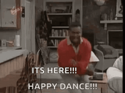 A Man In A Red Sweater Is Dancing In A Living Room With The Words `` It 'S Here ! '' GIF