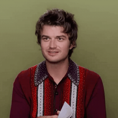 A Man In A Red Sweater Is Holding A Piece Of Paper In His Hand GIF