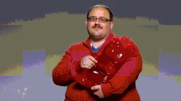 A Man In A Red Sweater Is Holding A Red Object In His Hands GIF