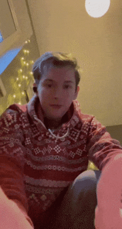 A Man In A Red Sweater Is Sitting On A Couch GIF