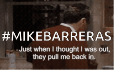 A Man In A Red Sweater Is Standing In Front Of A Sign That Says Mikebarreras GIF