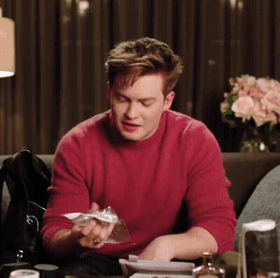 A Man In A Red Sweater Sits At A Table GIF