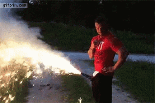 A Man In A Red T-Shirt Is Holding A Firework Display . GIF