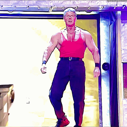 A Man In A Red Tank Top Is Standing In Front Of A Door GIF