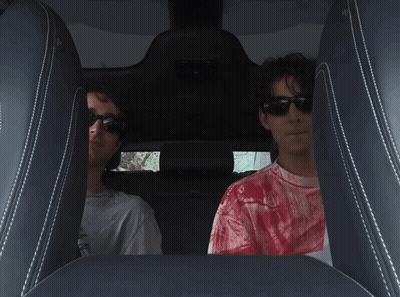 A Man In A Red Tie Dye Shirt Sits In The Back Seat Of A Car GIF