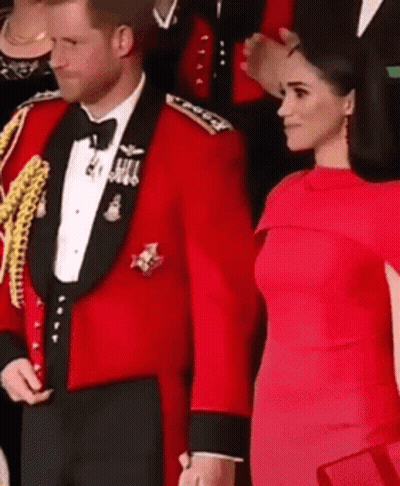 A Man In A Red Tuxedo And A Woman In A Red Dress Are Standing Next To Each Other And Holding Hands . GIF