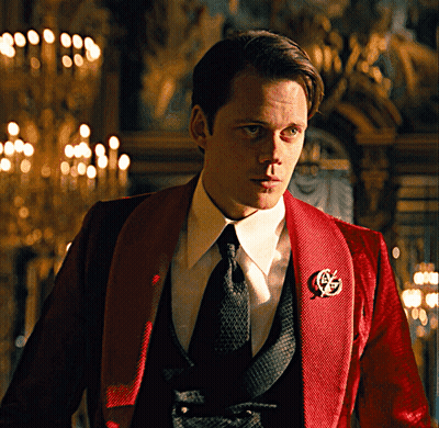 A Man In A Red Tuxedo Has A G On His Jacket GIF