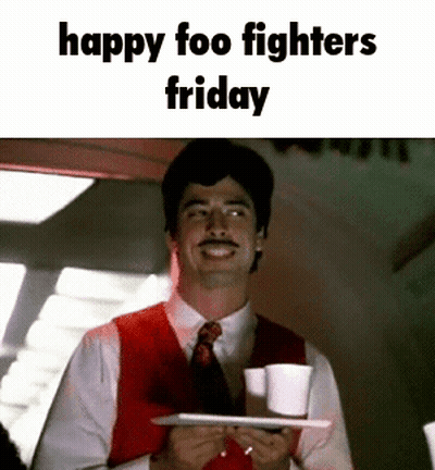 A Man In A Red Vest And Tie Is Holding A Tray Of Coffee Cups And Smiling . GIF