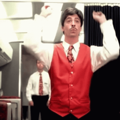 A Man In A Red Vest And Tie Is Raising His Arms In The Air GIF