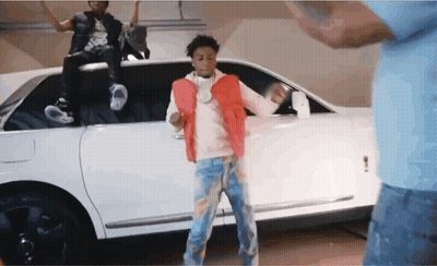 A Man In A Red Vest Is Dancing In Front Of A White Limousine GIF