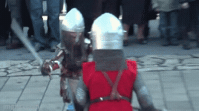 A Man In A Red Vest Is Standing Next To A Man In A Knight Costume GIF