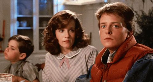 A Man In A Red Vest Sits At A Table With A Woman And A Boy GIF