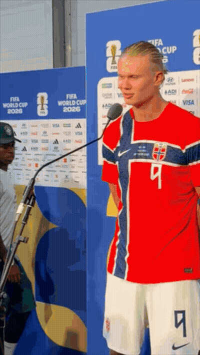 a man in a red white and blue jersey with the number 9 on it stands in front of a microphone