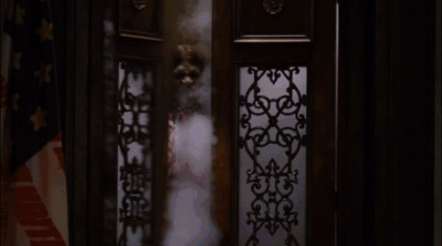 A Man In A Red White And Blue Outfit Is Standing In Front Of A Window GIF