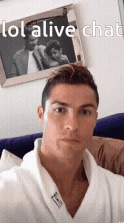 A Man In A Robe Is Sitting On A Couch In Front Of A Picture Of A Man And Woman . GIF