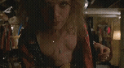 A Man In A Robe Is Standing In A Room With A Woman In A Blue Wig Behind Him . GIF