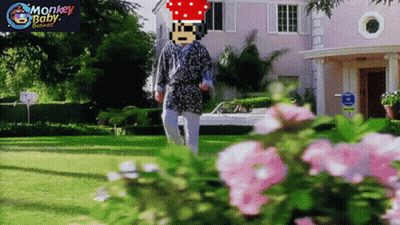 A Man In A Robe Is Walking In Front Of A Pink House With Monkey Baby Written On The Bottom Right GIF