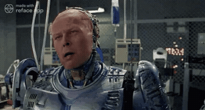 A Man In A Robot Suit Is Sitting In A Room With A Fence . GIF