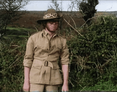 A Man In A Safari Outfit With A Leopard Print Hat And Glasses GIF