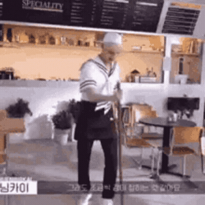 A Man In A Sailor Costume Is Standing In A Restaurant Holding A Sword . GIF