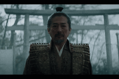 A Man In A Samurai Costume Stands In Front Of A Shrine GIF