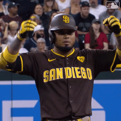 a man in a san diego baseball uniform holds his arms up