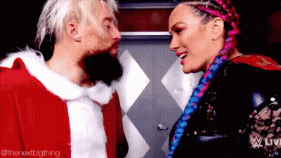 A Man In A Santa Claus Outfit Is Kissing A Woman In A Pink Braid . GIF