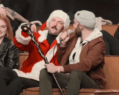 A Man In A Santa Suit Is Holding A Microphone GIF