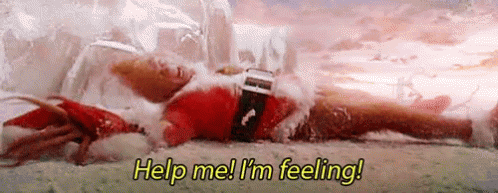 A Man In A Santa Suit Is Laying On The Ground In The Snow . GIF