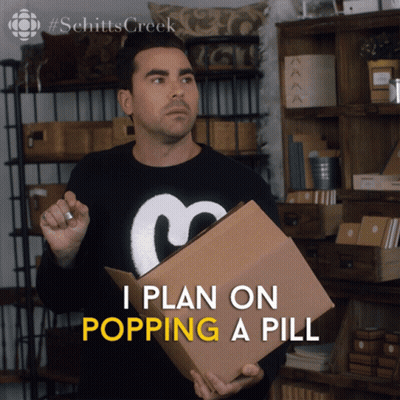 A Man In A Schitts Creek Sweater Holds A Cardboard Box GIF