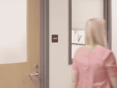 A Man In A Scrub Is Standing In A Doorway . GIF