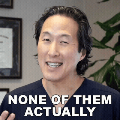 A Man In A Scrub Top Smiles With The Words None Of Them Actually Below Him GIF