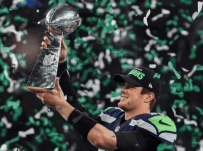 A Man In A Seahawks Hat Holds A Trophy GIF