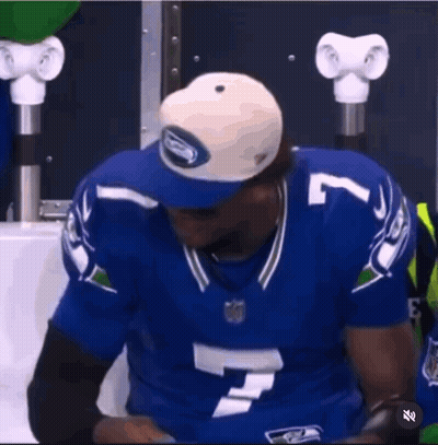 A Man In A Seahawks Jersey Is Holding A Tablet . GIF