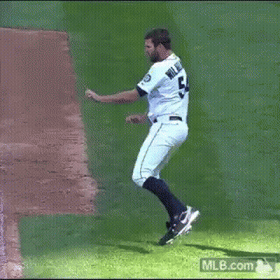 A Man In A Seattle Mariners Uniform Is Dancing On The Field GIF