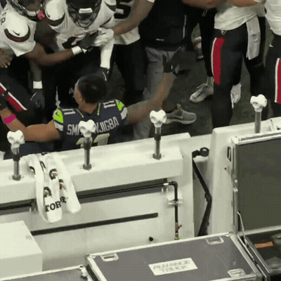 A Man In A Seattle Seahawks Jersey Is Surrounded By Other People GIF