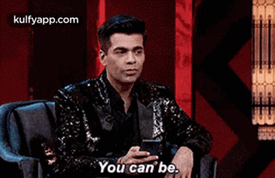 A Man In A Sequined Jacket Is Sitting In A Chair Holding A Cell Phone And Saying `` You Can Be . '' GIF