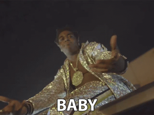A Man In A Sequined Jacket With The Word Baby Above Him GIF