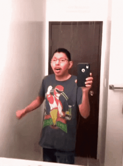 A Man In A Sesame Street Shirt Is Taking A Picture Of Himself In The Mirror GIF