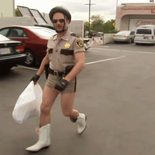 A Man In A Sheriff 'S Uniform Is Carrying A Bag And Wearing Cowboy Boots GIF